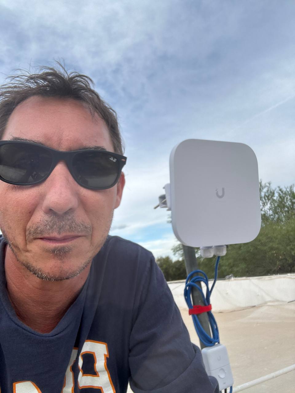 Drew beside a UniFi outdoor network device during a Tucson installation
